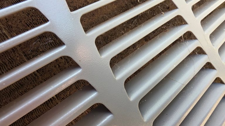 Outdoor HVAC condenser coil clogged with dirt, lint, and debris