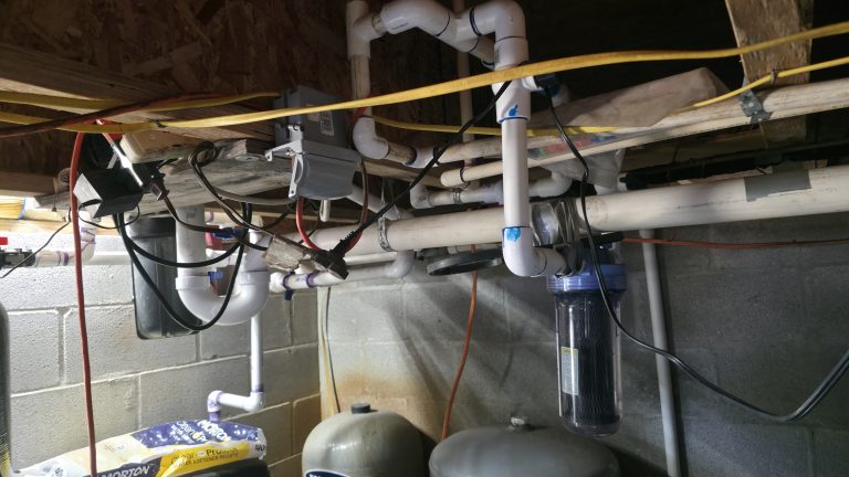 Extension cords and electrical connections installed near basement plumbing