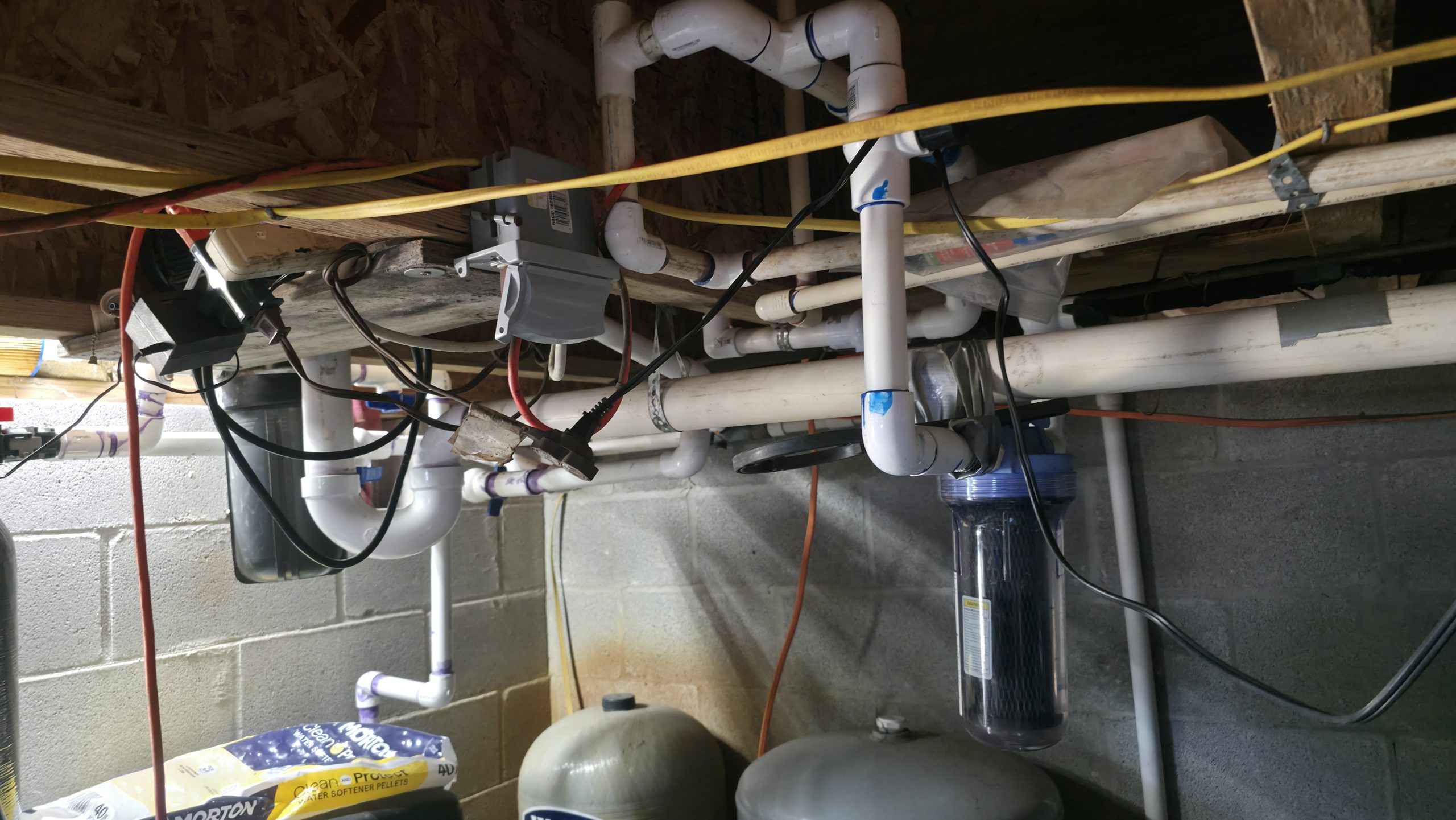 Extension cords and electrical connections installed near basement plumbing