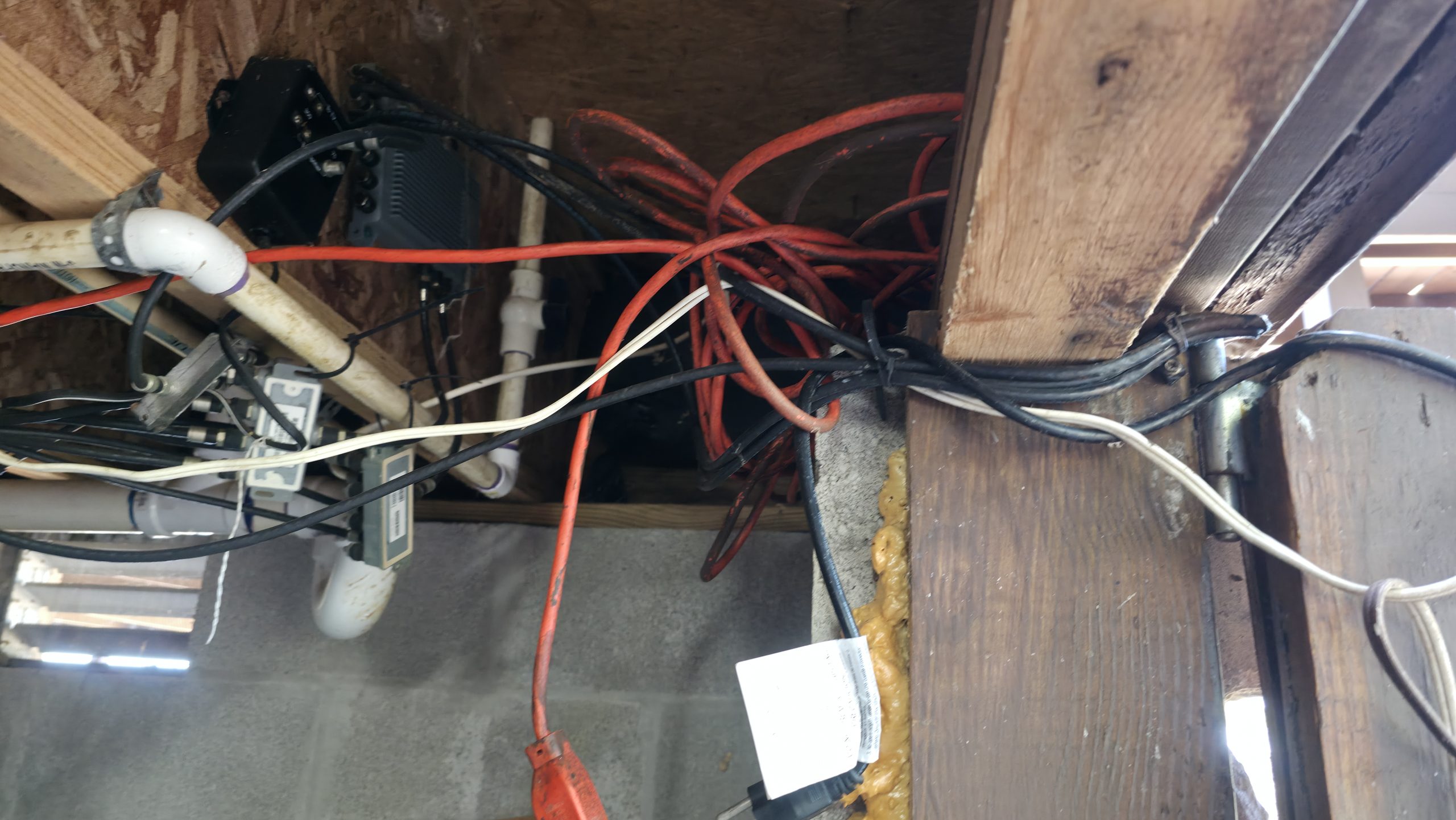 Multiple extension cords used around exposed framing in a basement utility area