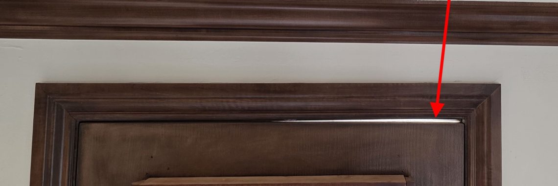 Daylight visible through a gap between the top of an exterior door and its frame