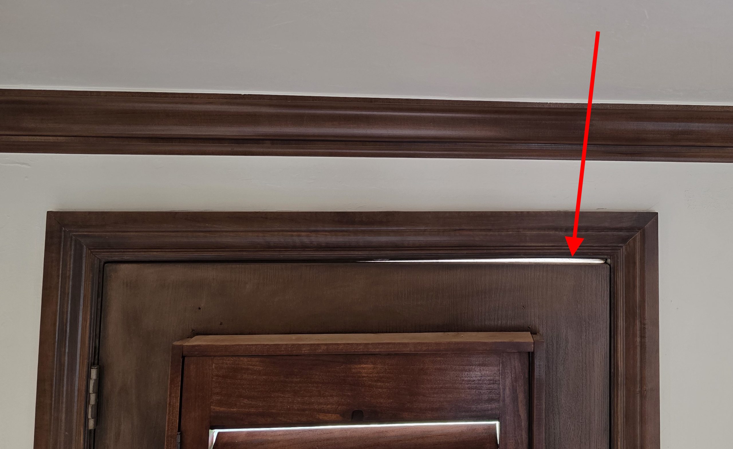 Daylight visible through a gap between the top of an exterior door and its frame